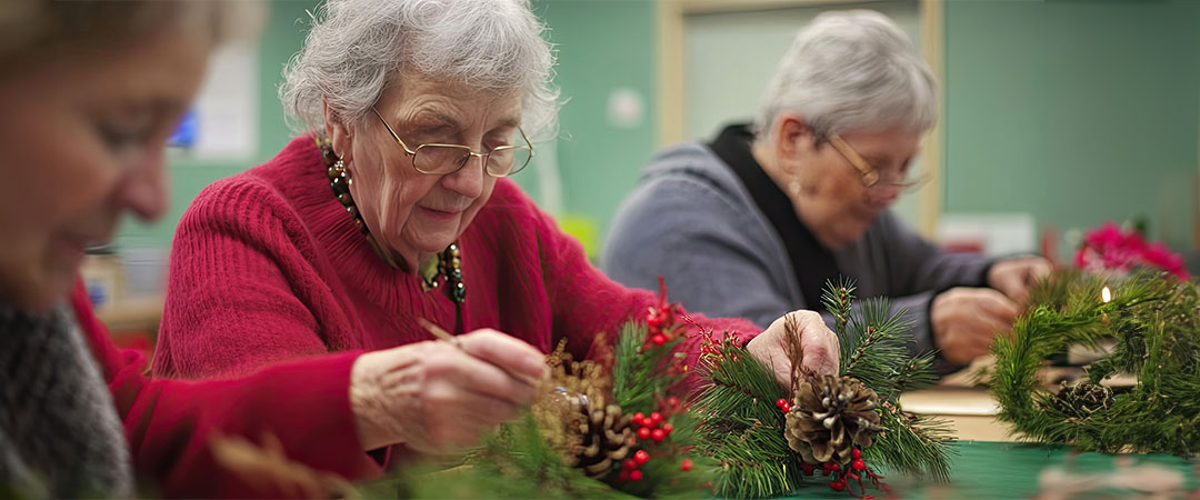 Three seniors sat at a table doing holiday activities.